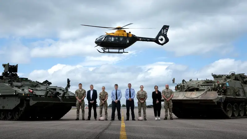 UK Armed Forces personnel on the airfield with armoured vehicles and helicopter